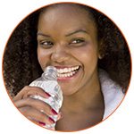 Jeune femme souriante qui boit de l'eau