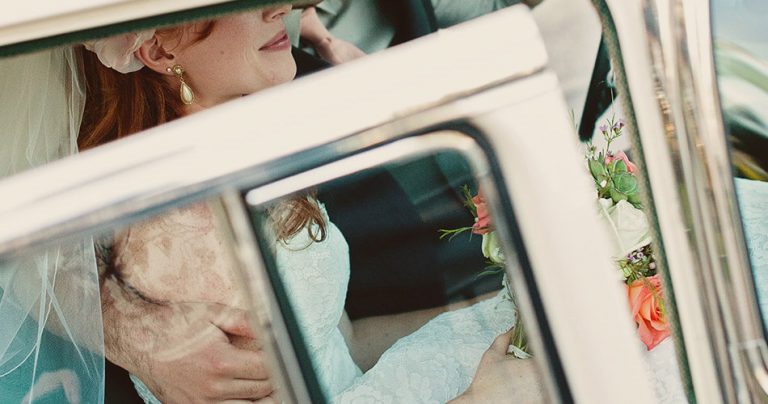 Couple de jeunes mariés à travers la fenêtre de leur voiture