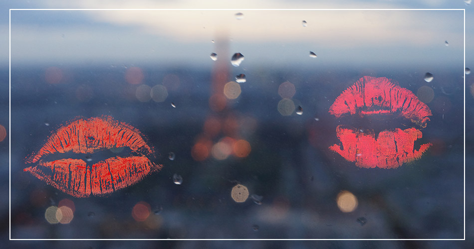 Marques de 2 kiss au rouge à lèvre sur une vitre
